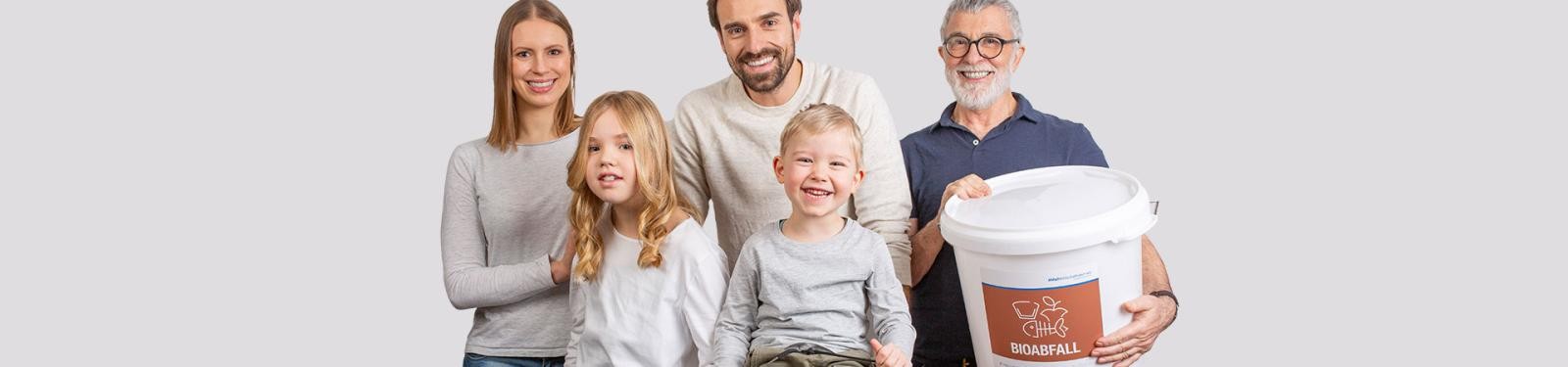 Anmeldung zur Abfallentsorgung Eine Familie lächelt in die Kamera; der Großvater hält einen Bioabfallbehälter