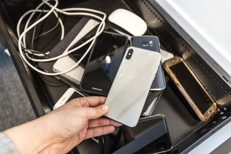 Ein Mann hält ein altes Handy das in einer Schulblade liegt