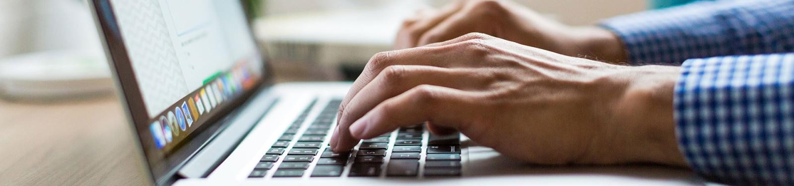 Sperrmüll anmelden Zwei Hände tippen etwas in einen geöffneten Laptop ein