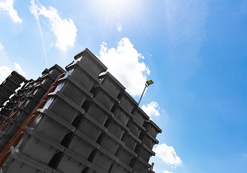 Viele neue schwarze Mülltonnen übereinander gestapelt, daneben strahlend blauer Himmel