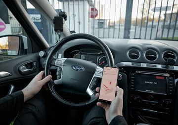 Ein Autofahrer schaut auf ein Handy mit App